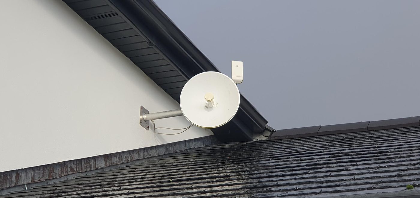 White wireless link dish on a wall bracket