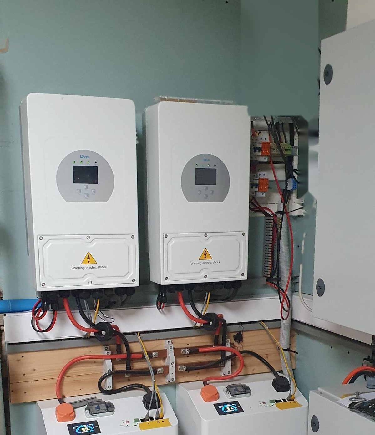 Two hybrid inverters above two battery storage units with copper busbars