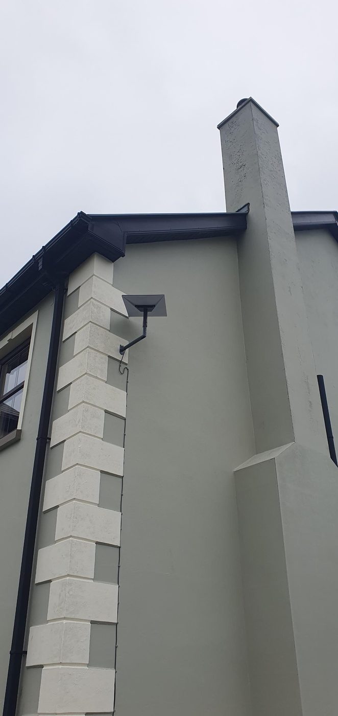 Starlink on a wall bracket on a green rendered house