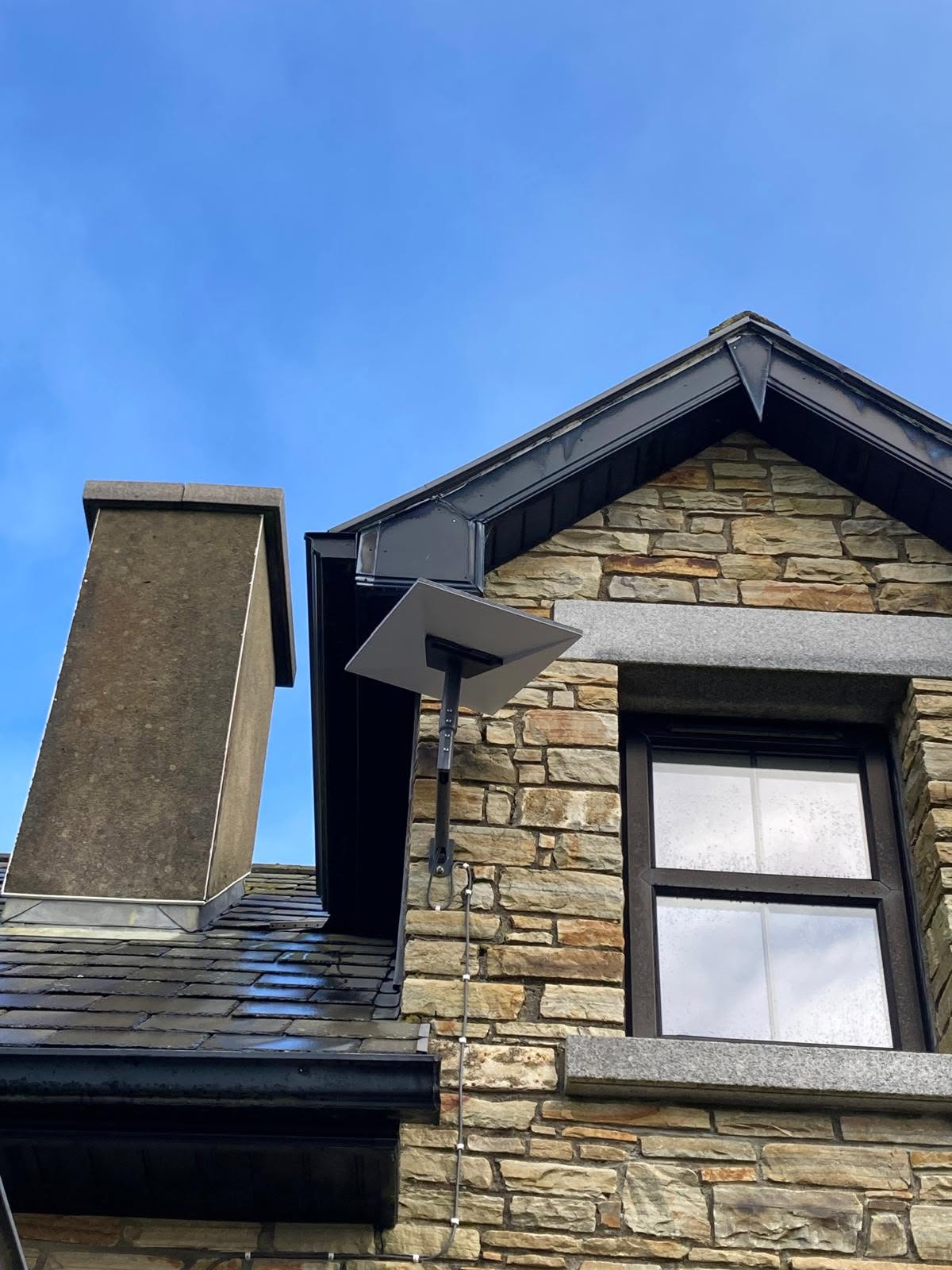 Starlink dish mounted on a gable wall of a stone-faced house in Donegal